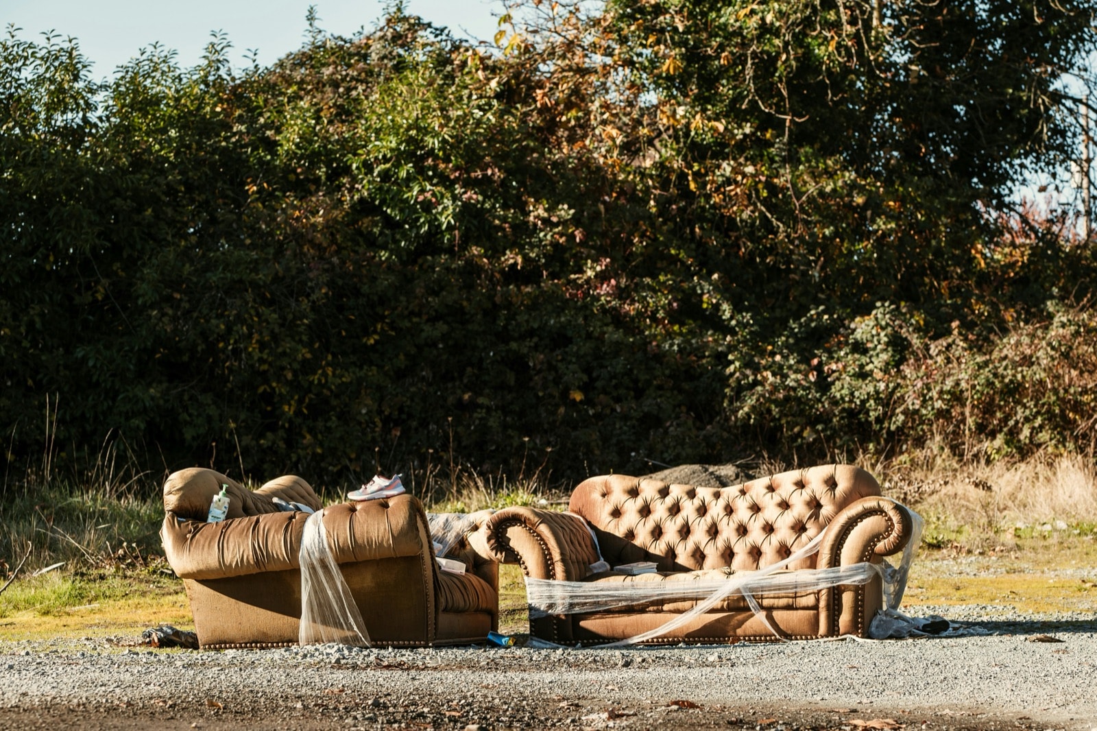 Old tufted sofa and armchair left outside, waiting for couch removal