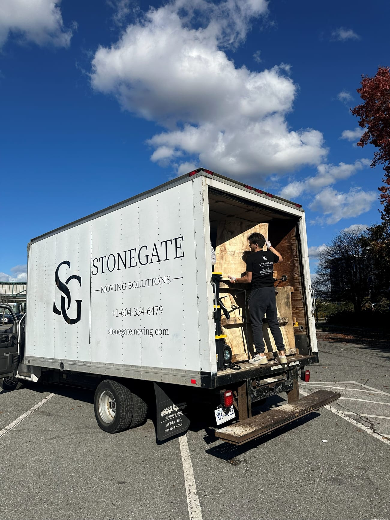 Branded Stonegate junk removal truck with a crew member loading the back
