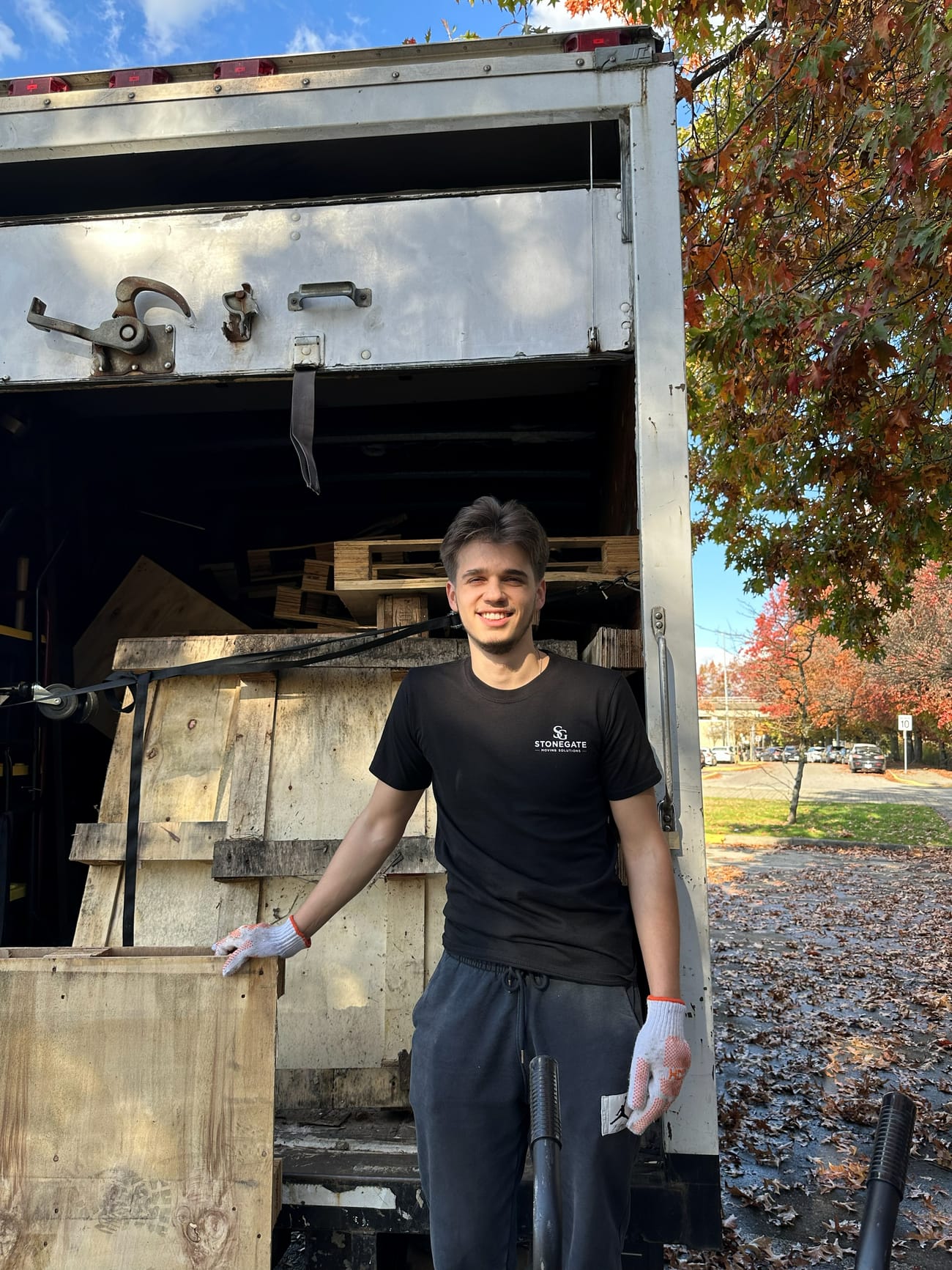 Smiling Stonegate crew member standing in the back of the junk removal truck