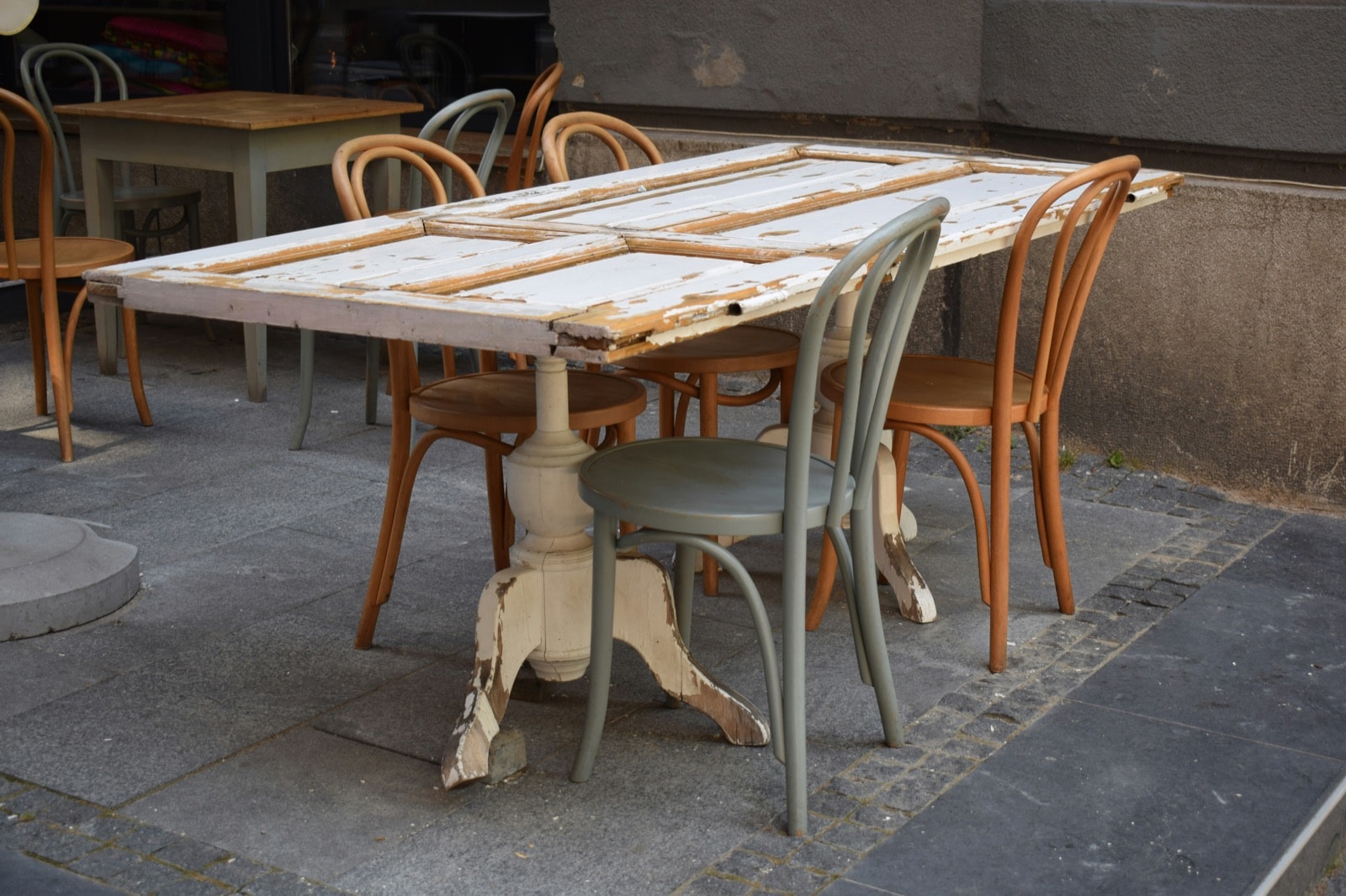 Worn white wooden table with peeling paint and bentwood chairs, ready for table and chair removal